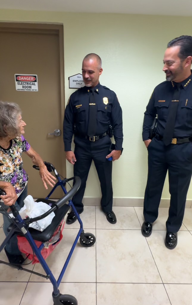 two officers speaking with a lady leaning on a walker.