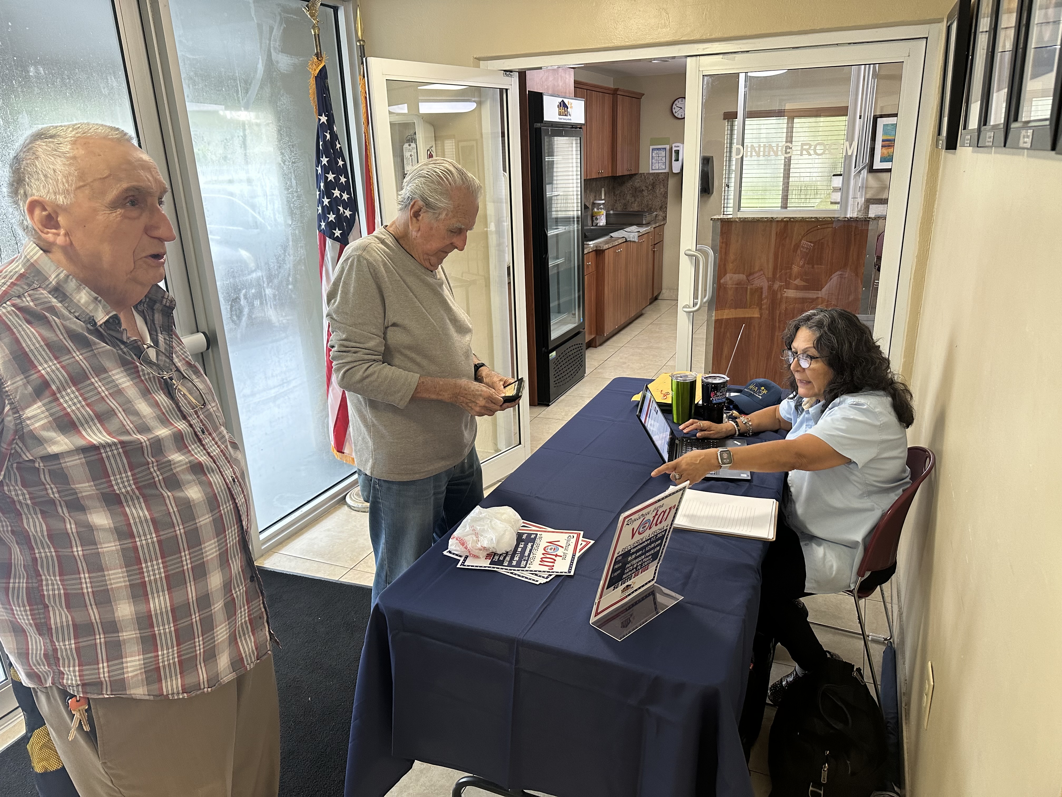 woman behind a table helping people register to vote.
