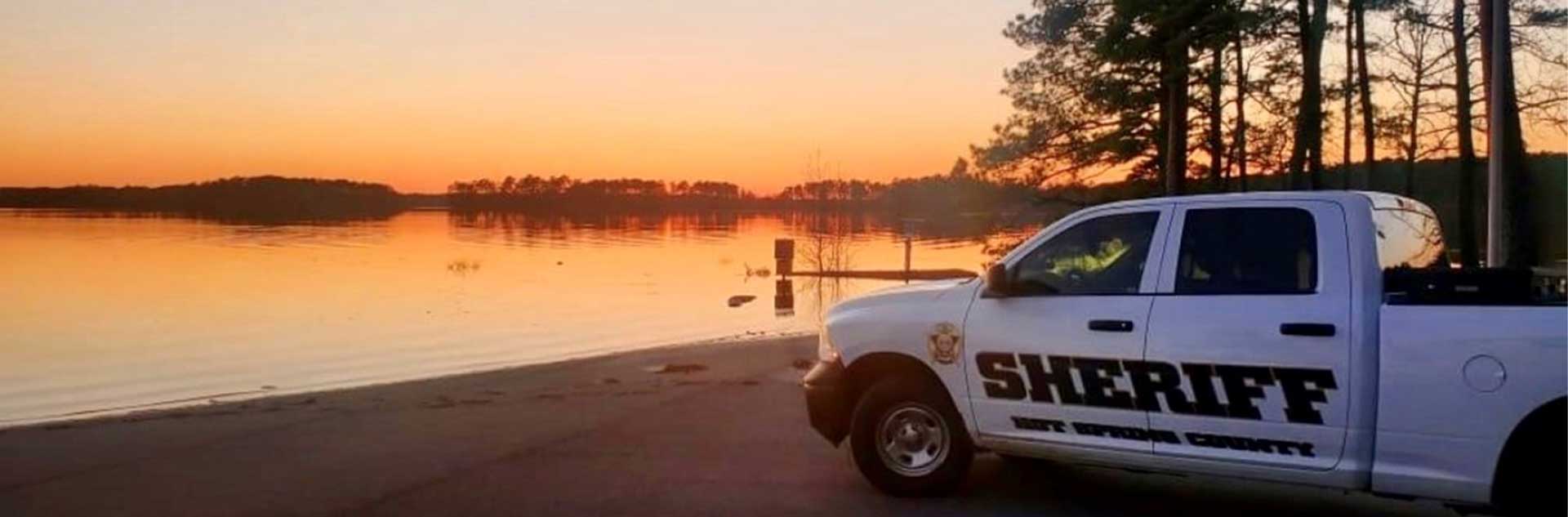 A Hot Spring County Sheriff patrol truck in front of a lake at sunset.