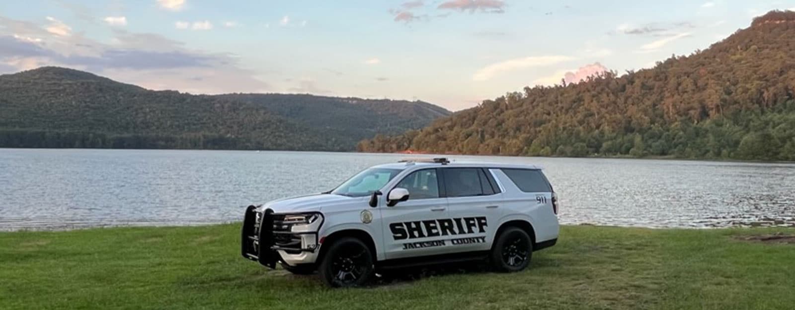 Jackson County Sheriff's Office patrol vehicle in front of a lake and mountain landscape.