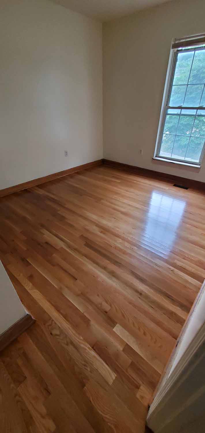 A bedroom with beautiful hard wood flooring.