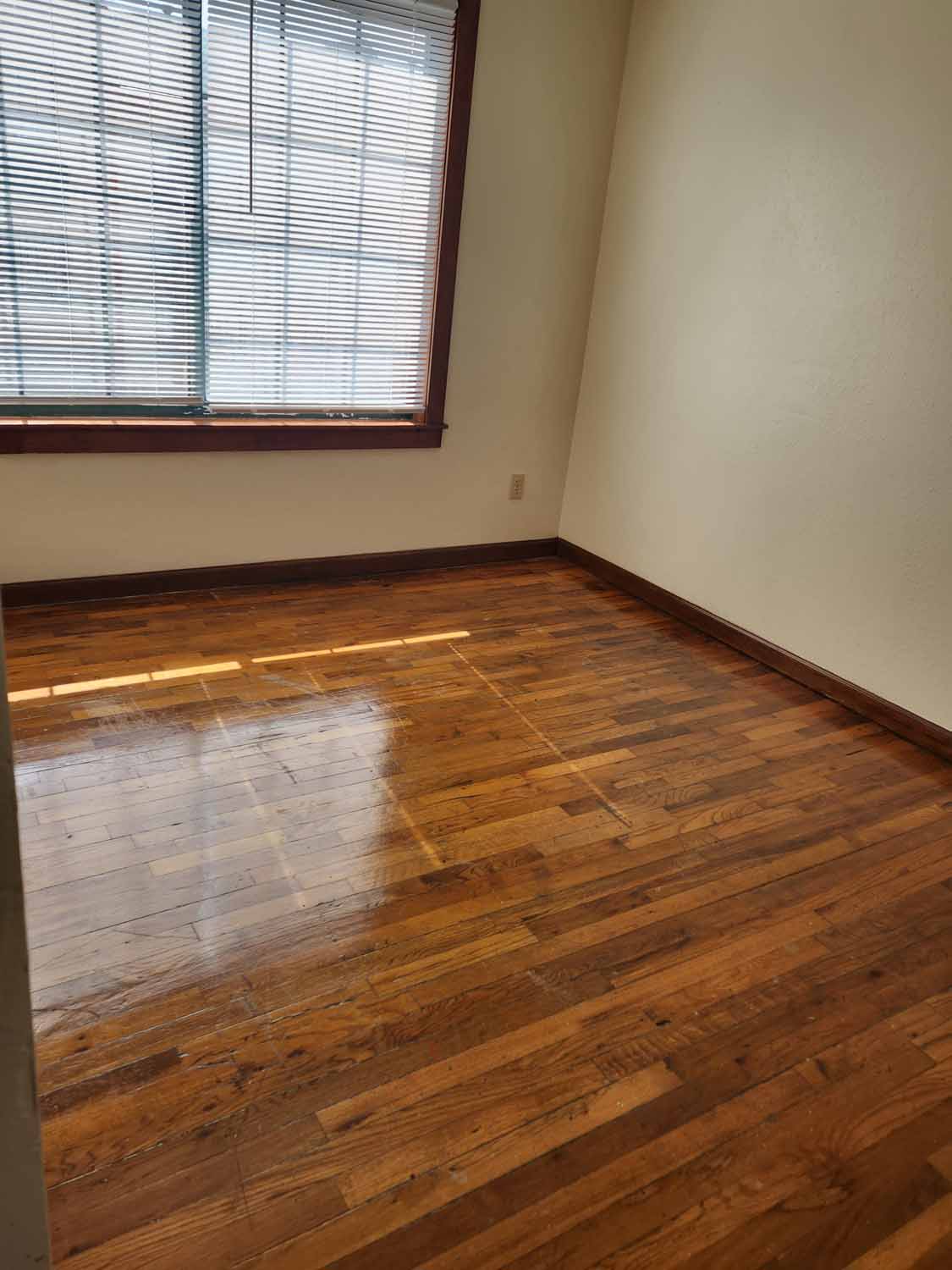 A bedroom with shiny hard wood flooring.