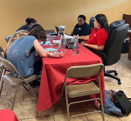 People discussing the TRIO program while seated at a table and looking at paperwork.