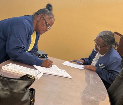 People sitting at a table doing paperwork.