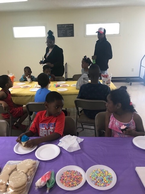 Tables with children eating cupcakes and getting ready to decorate cookies.
