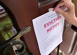 Hand taping an eviction notice on a door.