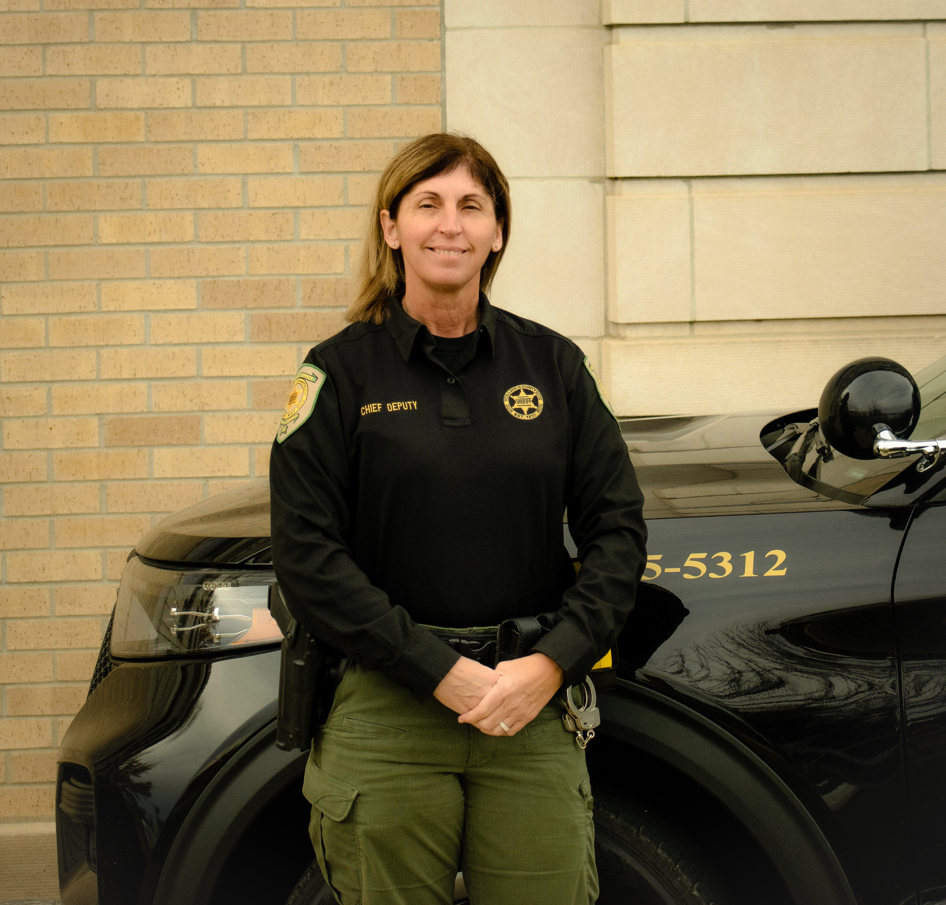Chief Deputy Carrie Pfeifer standing in front of her patrol vehicle. 
