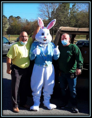 Two men standing on either side of the Easter Bunny.