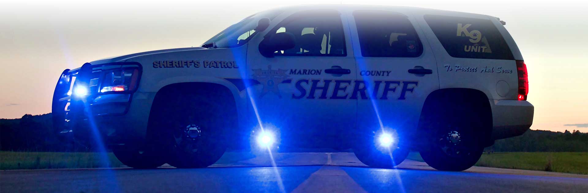 A Marion County Sheriff Patrol SUV in the road with its lights on.