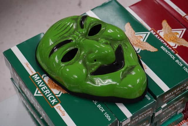 A Halloween mask on top of cigarette boxes.
