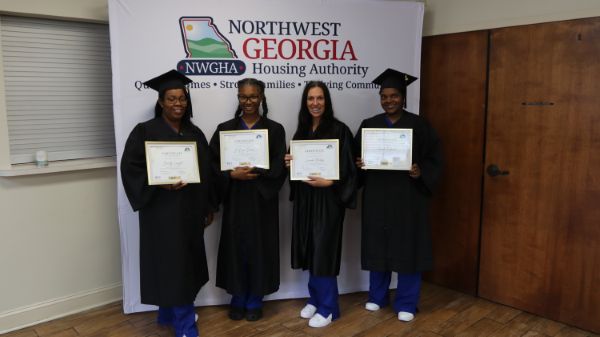 Four graduates holding their certificates.