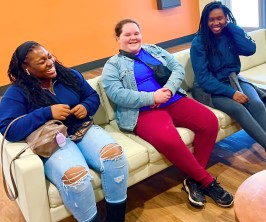 Girls laughing on a couch.