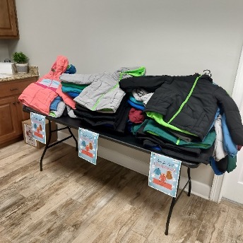Table filled with coats for the giveaway.