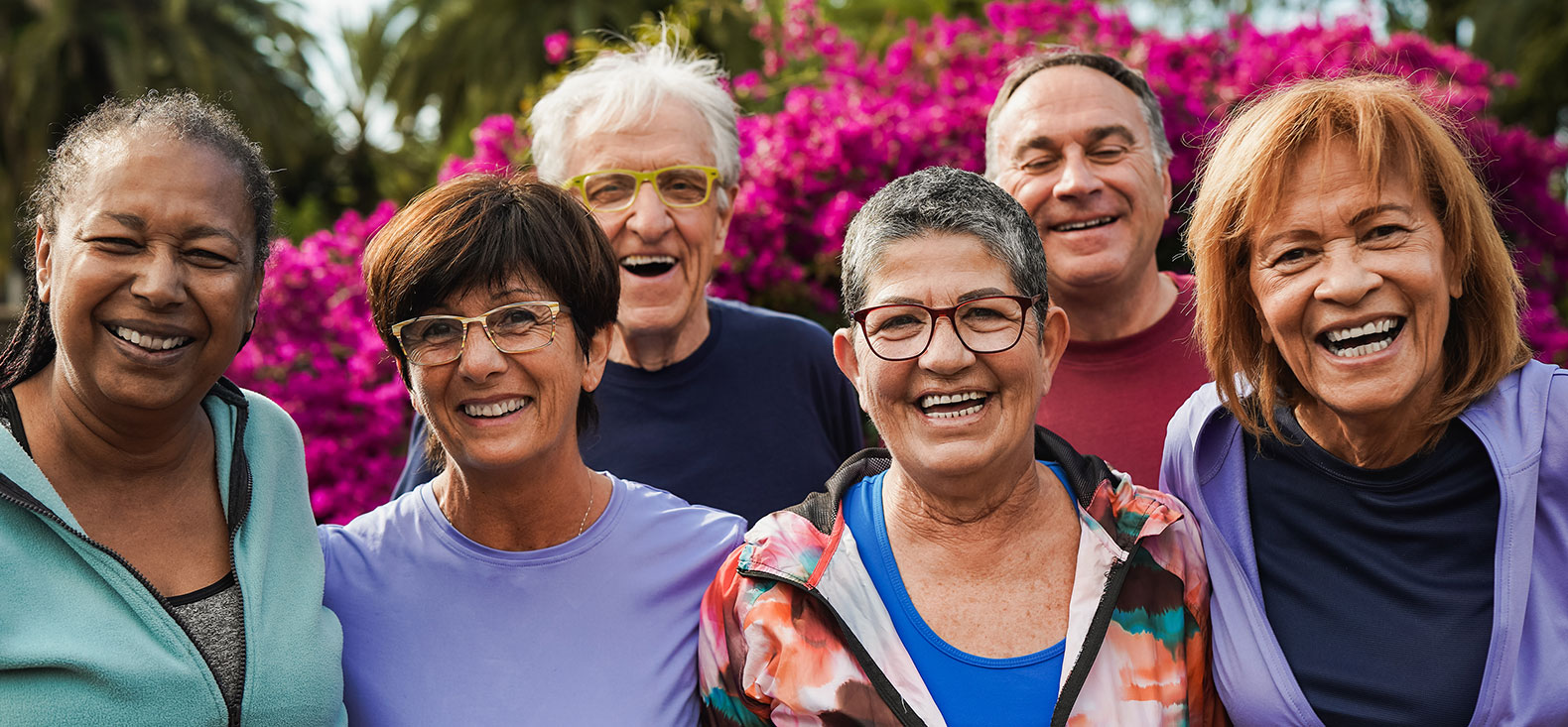 Group of adults outdoors in front of a red bush.