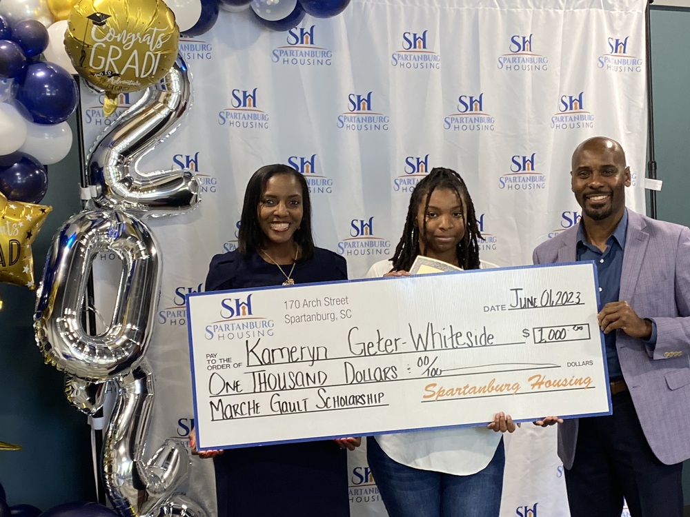 Three people holding a scholarship check with Kameryn Geter-Whiteside in the middle.