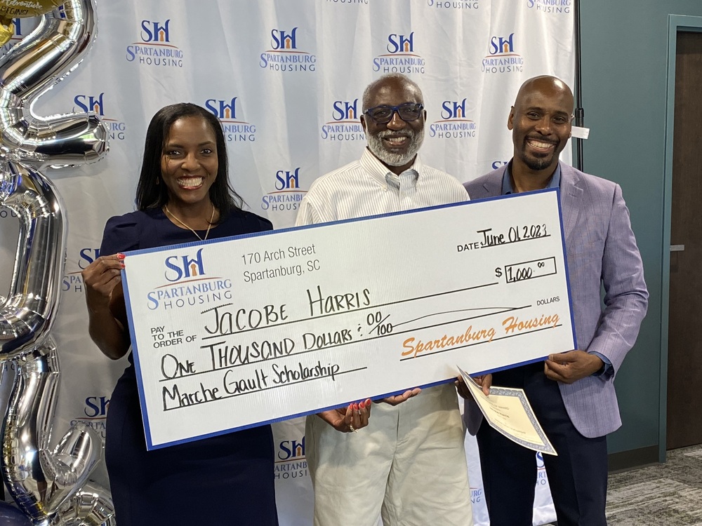 Three people smiling holding a scholarship, with Jacob Harris in the middle.