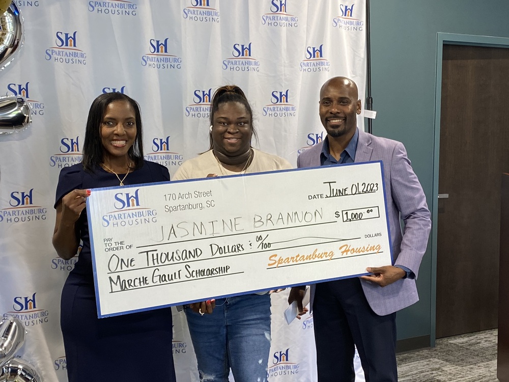 Three people holding a scholarship check, with Jasmine Brannon in the middle.