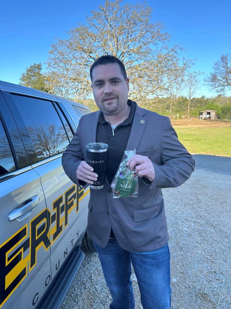 Sheriff carrying a mug and a goody bag.