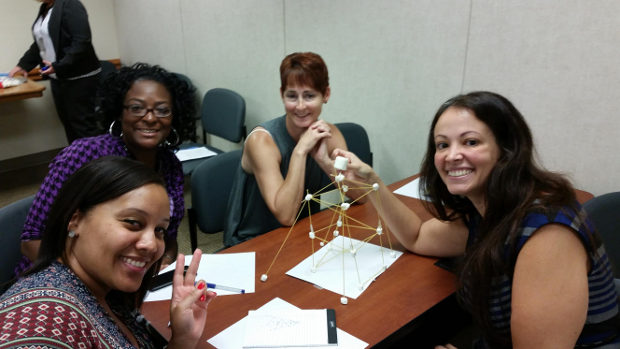 Team members sitting at a table smiling with their crafts.