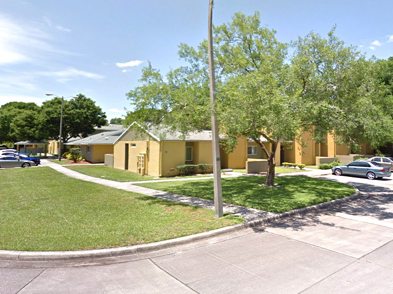 A yellow home with a tree in the front yard.