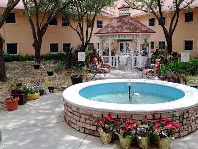 A pink building with a fountain in the yard.