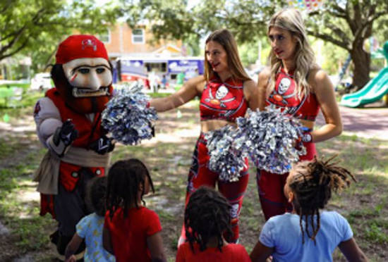 Cheerleaders and a mascot talking to children.