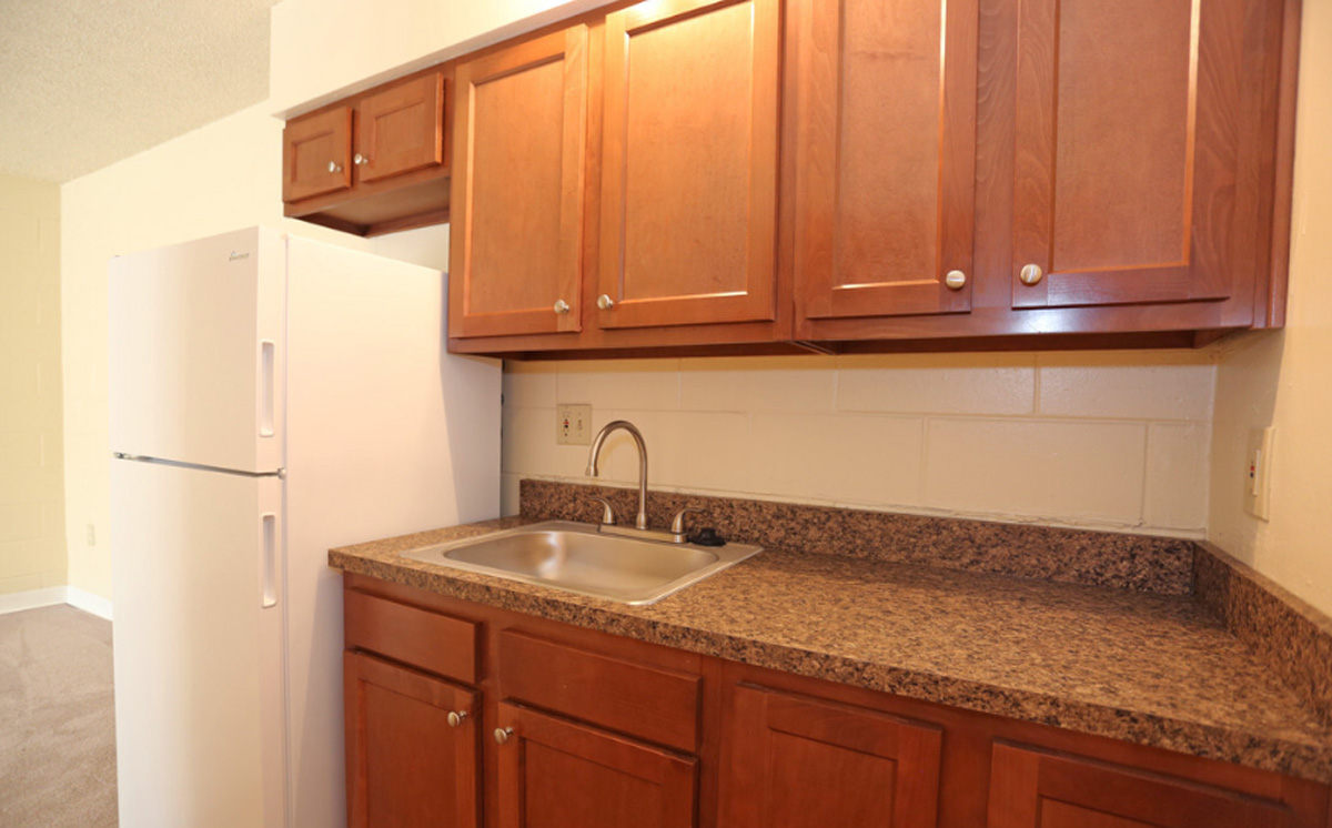 A kitchen countetop with a sink and a refrigerator to the left.