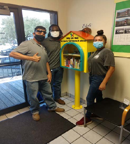 Three individuals standing by a book house.