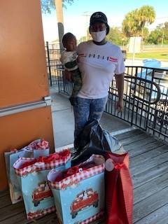 Individual holding a child while standing by three bags.