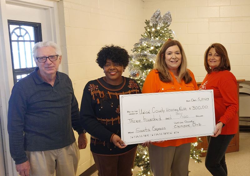 Four people holding a check from the Clemson Club.