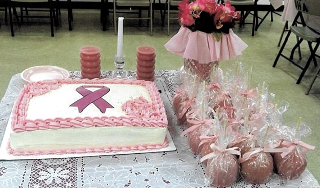 A pink cake on a table with candied apples. 
