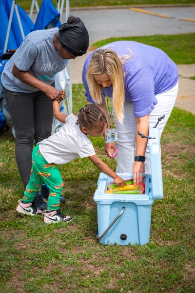 Child picking out a book from a tote.