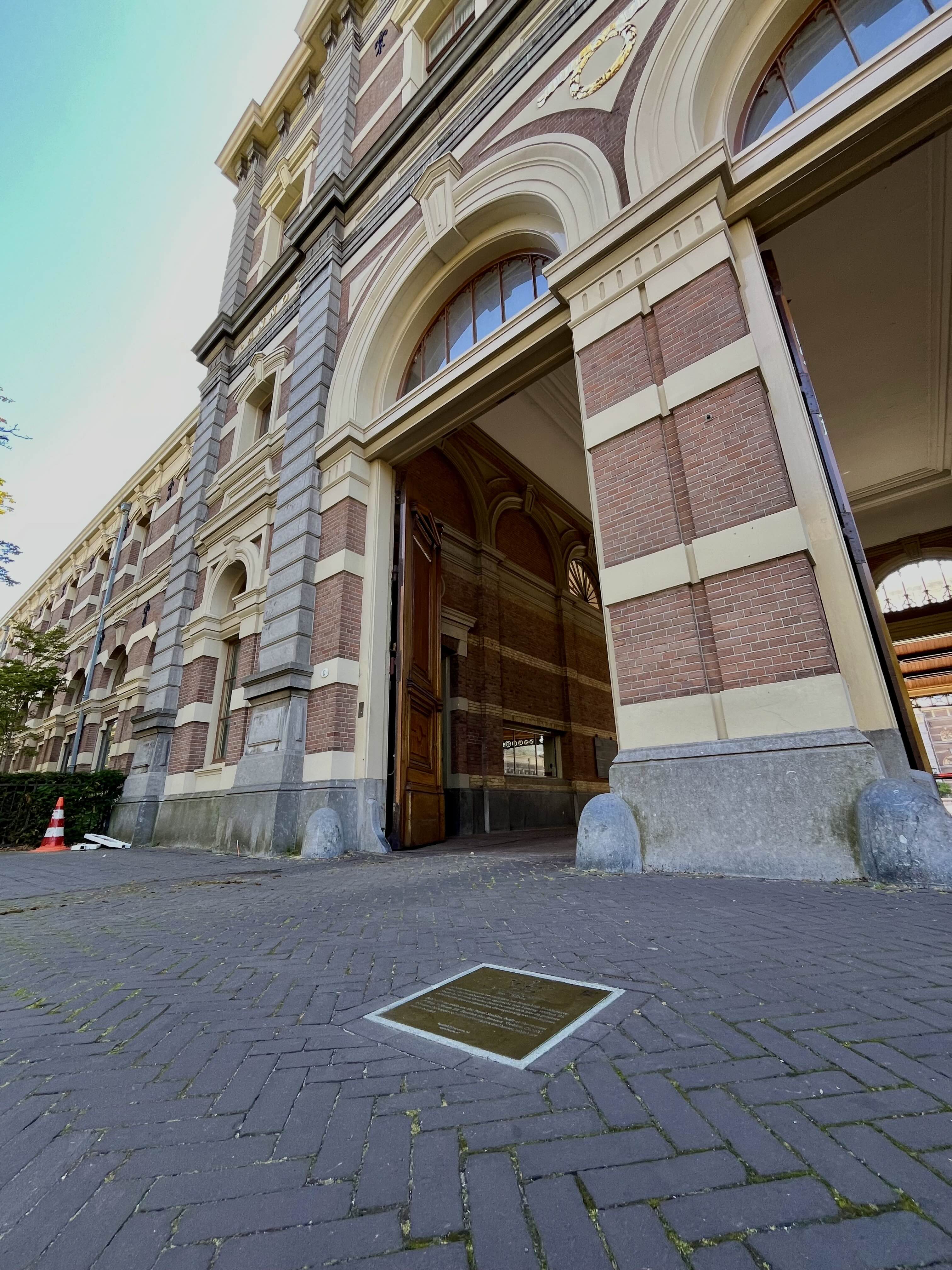 This plaque informs that you're standing in front of the "koninklijke stallen": the royal stables. It holds a description in English: "Behind these walls are the Royal Stables, built at the...