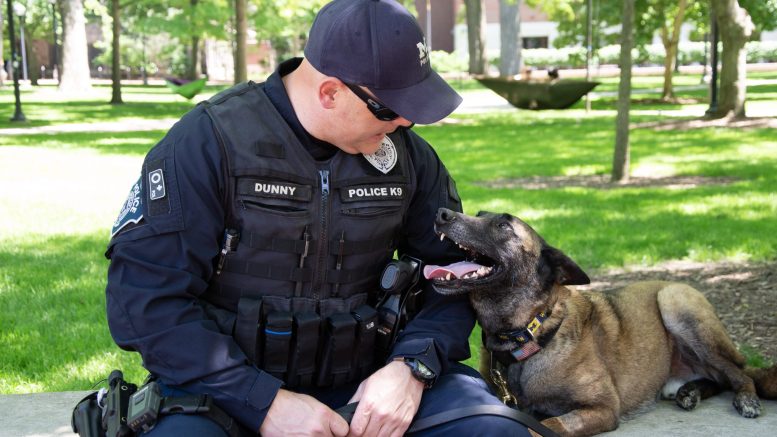 Officer Joseph Dunny and K-9 Tank sit together on the Diag