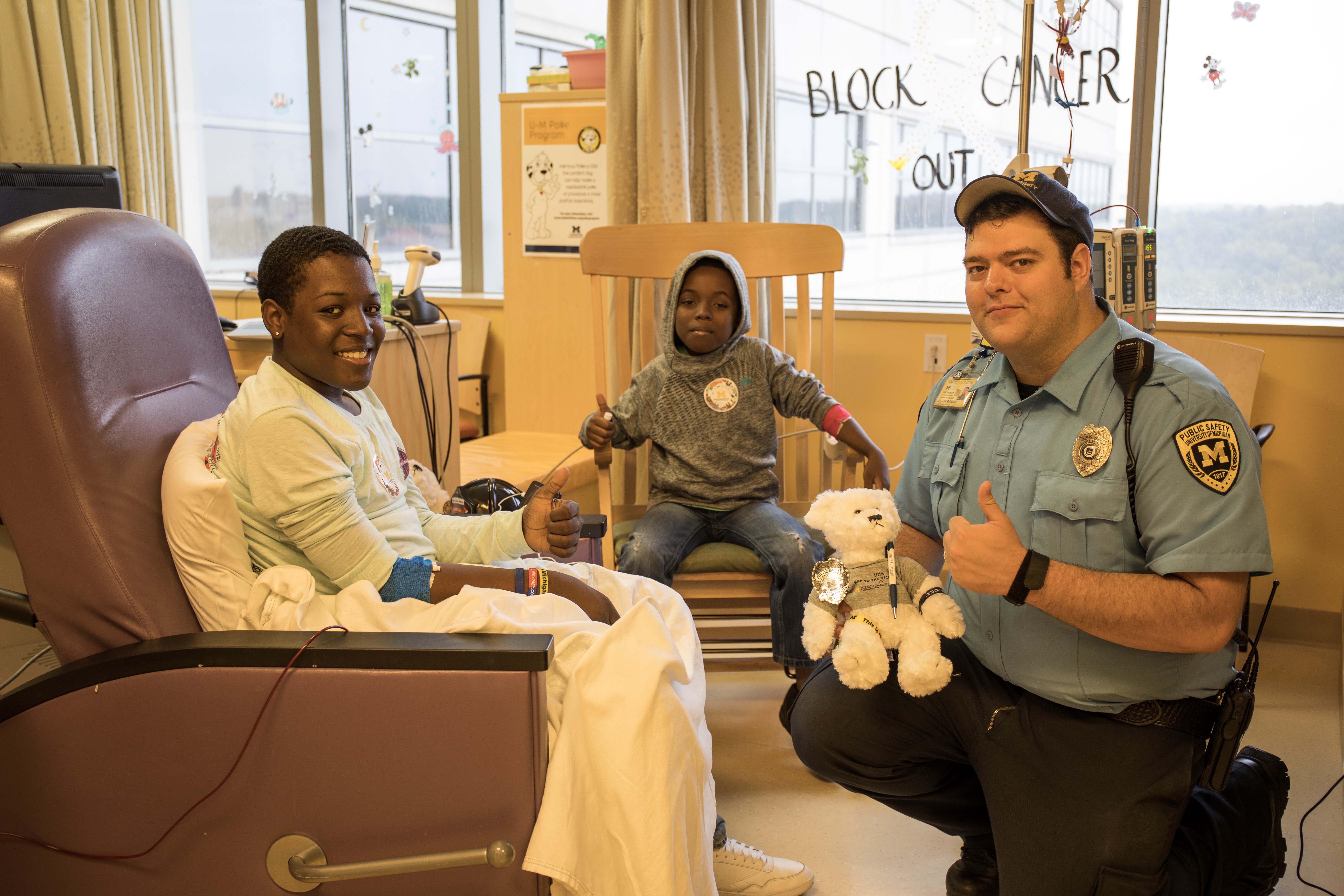 Security Officer Roman gives a thumbs up with two patients receiving treatment