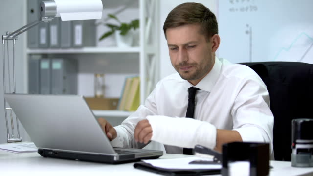 Homem com braço quebrado mexendo no computador. ARIA com certeza pode ajudar neste tipo de situação.