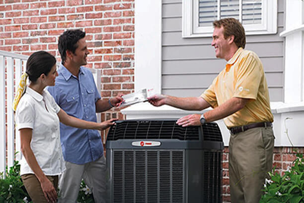 Salesman Handing A Brochure To Couple About Air Conditioning Units.