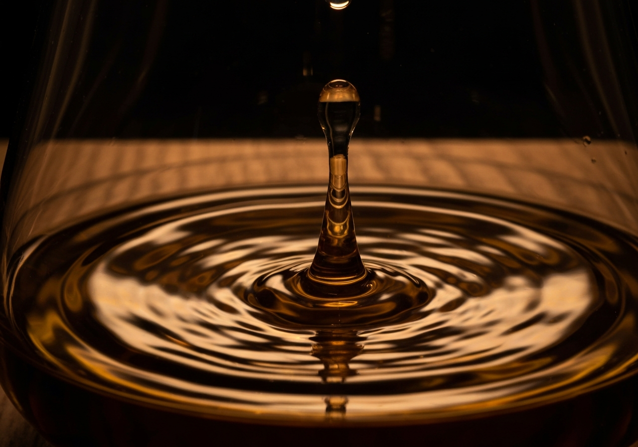 A close-up, high-speed photography shot of a single drop of amber whisky hitting the surface of a dram, creating ripples.