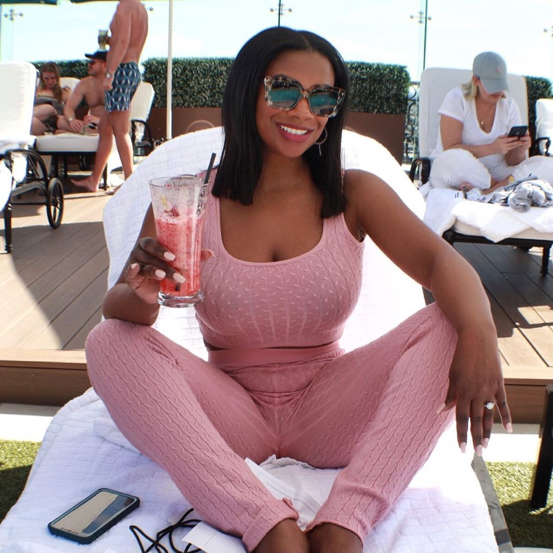 A photo of Kandi Burruss in a pink two-piece outfit while holding a drink.