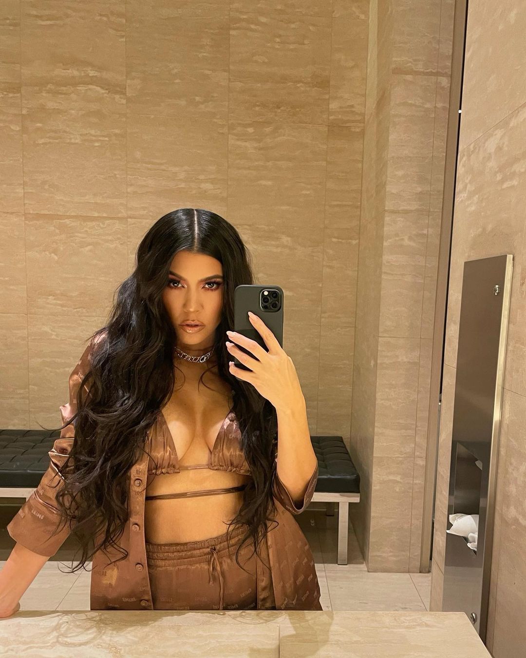 A photo showing Kourtney Kardashian posing for a mirror selfie in a huge bathroom.