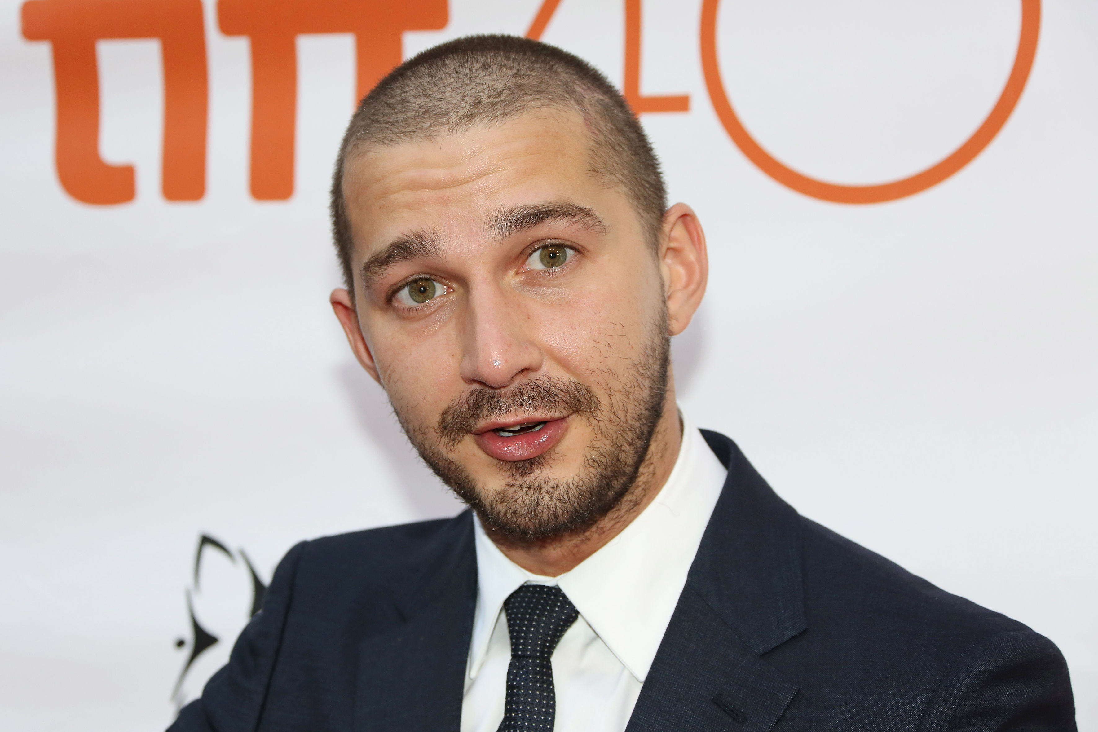 A throwback photo of Shia LaBeouf, seen wearing a black suit and polka dotted tie, paired with a plain white inner T-shirt.