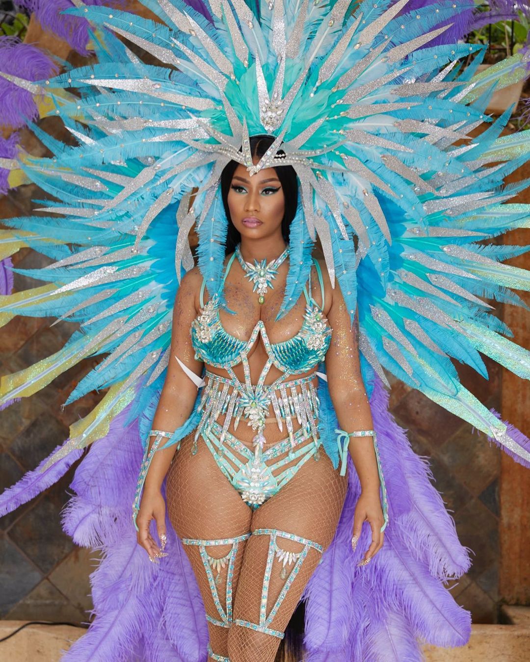 A lovely photo showing Nicki Minaj in a Trinidad costume, made up of a lingerie, with a huge wing attached with it, made from feathers.