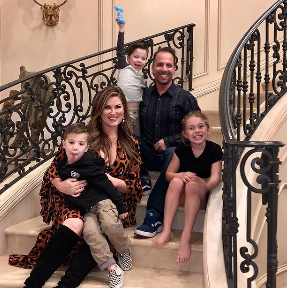 Emily Simpson sits on the stairs with husband Shane and their kids.