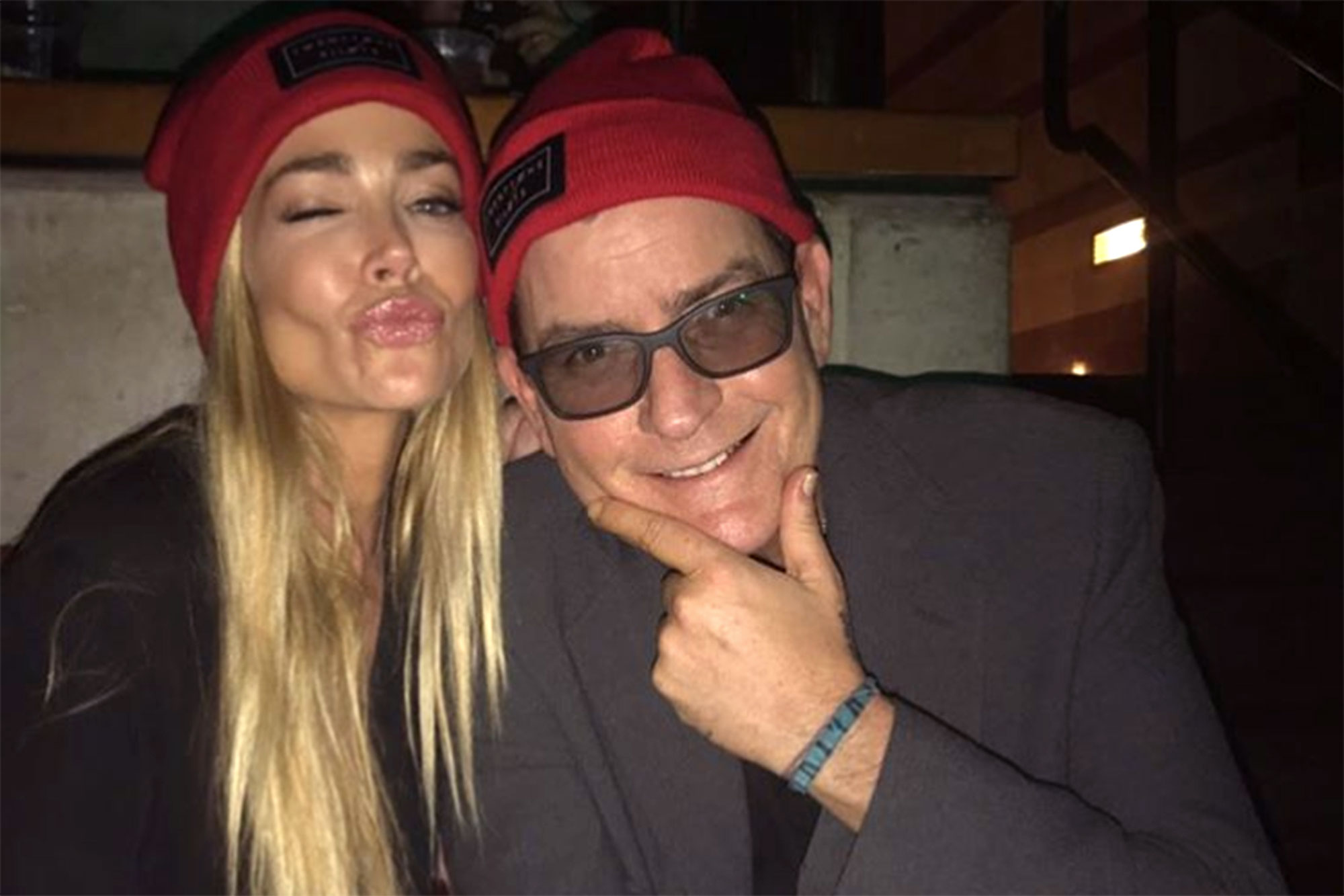 Charlie Sheen smiles as ex-wife Denise Richards gives kissing lips.