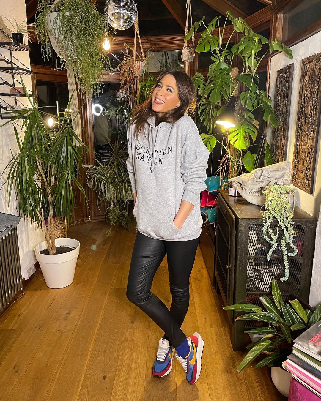 A photo showing Lisa Snowdon sporting a gray hoodie and black leather pant in the comfort of her home.