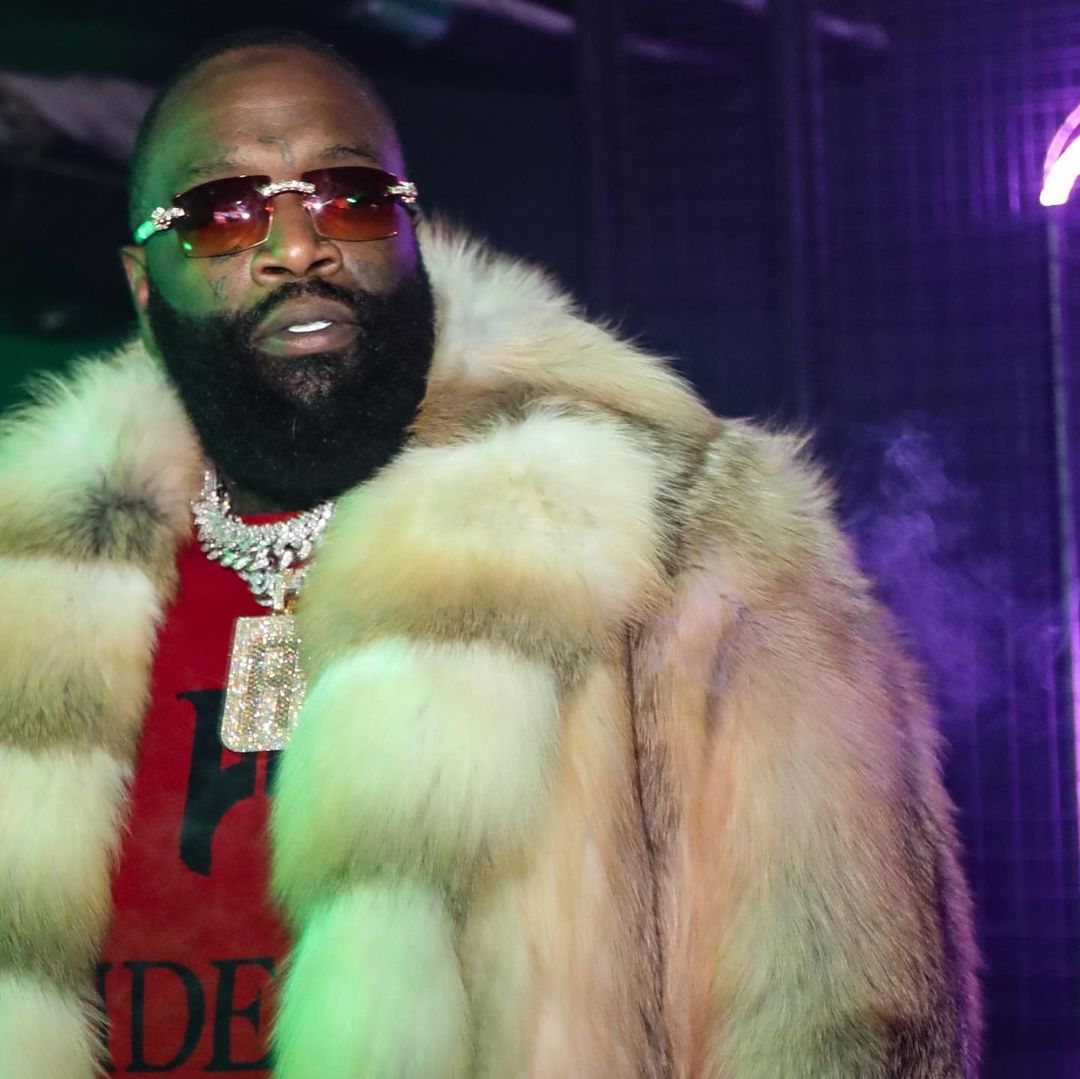 A photo showing rapper Rick Ross rocking a red shirt and brown fur jacket.