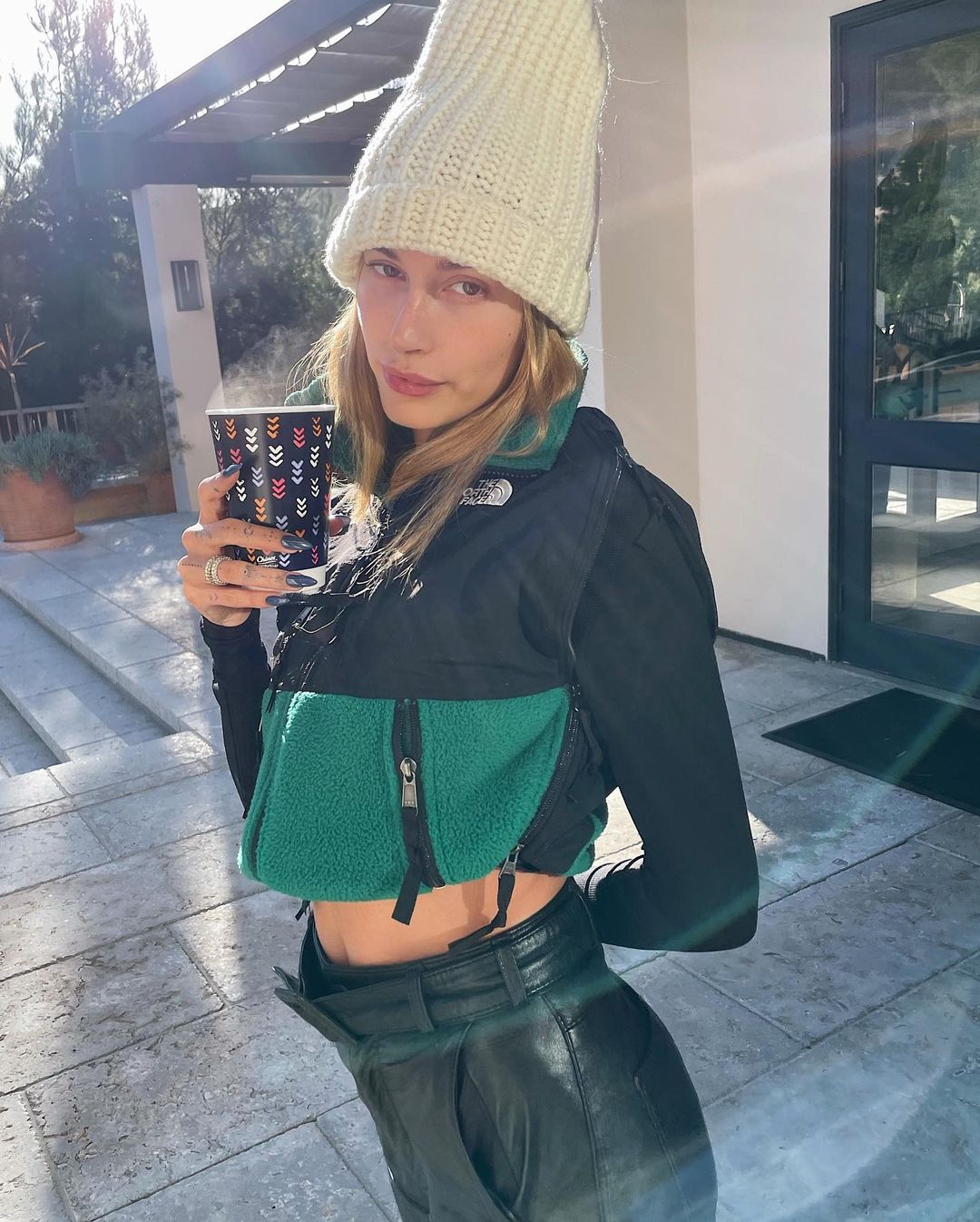 A lovely photo showing Hailey baldwin in a crop-top jacket, a black leather pant and a white beanie on her head.