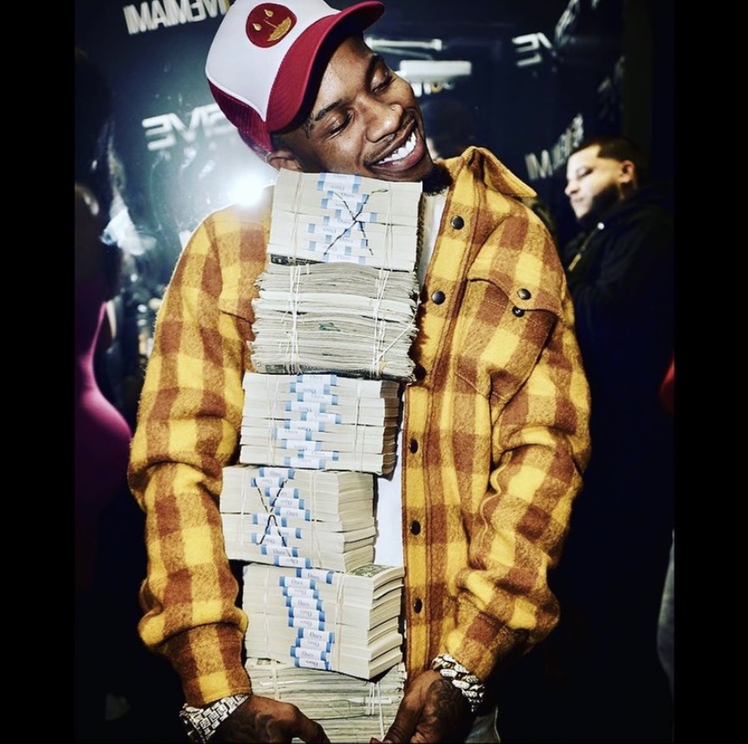 Lanez in a nightclub with stacks of money.