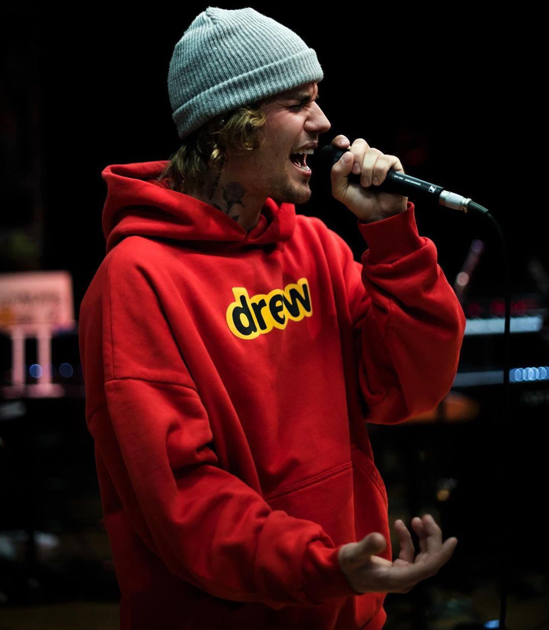 a cute photo of Justin Bieber in an orange hoodie with a microphone in his hand.