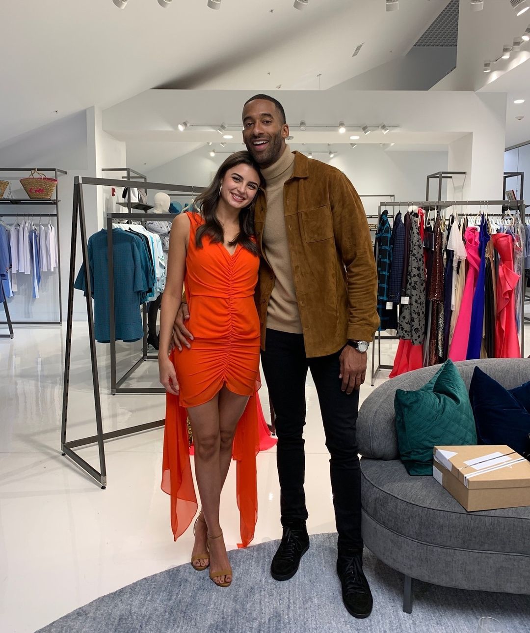 A photo showing Matt James and Rachael Kirkconnell posing beautifully for a photo at a clothing store.